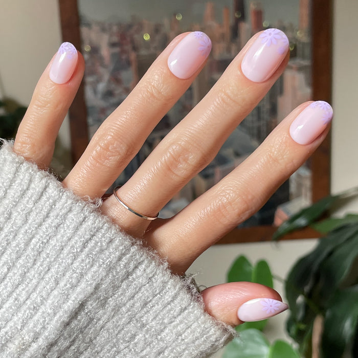 Floral Tip | Short | Round - Tab Press-On with neutral base and subtle lavender floral designs at the nail tips on hand indoors