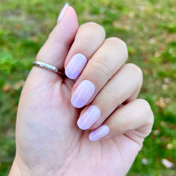 Floral Tip | Short | Round - Tab Press-On nails with neutral base and soft lavender floral accents on hand outdoors