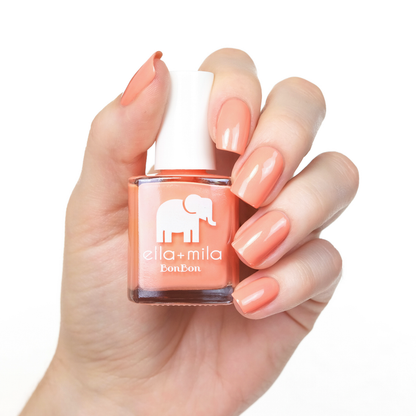 French Kiss peachy coral nail polish manicure on a light skin tone with the bottle