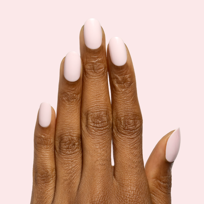 Gelato | Short | Round - Tab Press-On soft baby pink press-on nails on hand with smooth mani finish against pale pink background