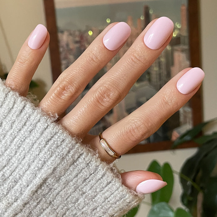 Gelato | Short | Round - Tab Press-On soft baby pink press-on nails with glossy manicure on hand in cozy sweater indoors