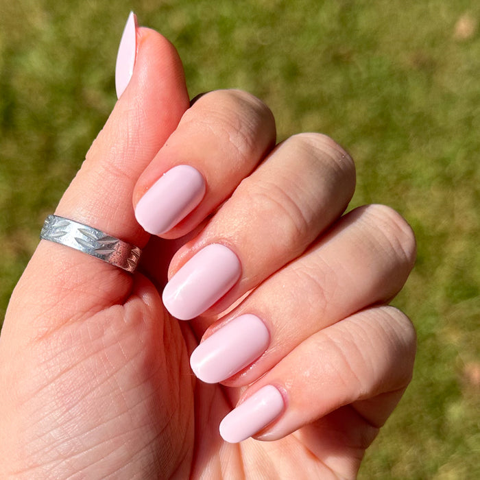Gelato | Short | Round - Tab Press-On soft baby pink nails with glossy smooth finish on hand outdoors in natural light