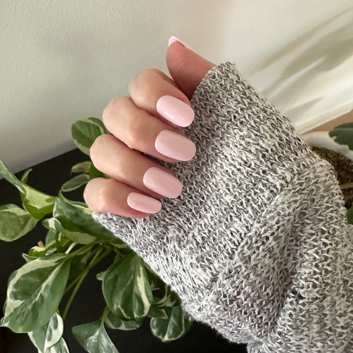 Gelato | Short | Round - Tab Press-On soft baby pink press-on nails with smooth glossy finish on hand wearing gray knit sweater