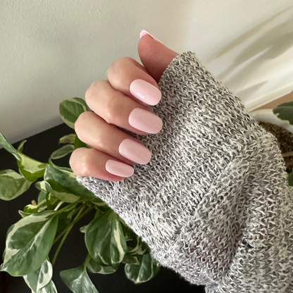 Gelato | Short | Round - Tab Press-On soft baby pink press-on nails with smooth glossy finish on hand wearing gray knit sweater