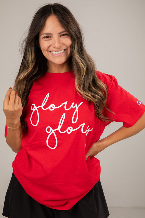 Woman wearing a red t-shirt with 'glory glory' text on a plain background