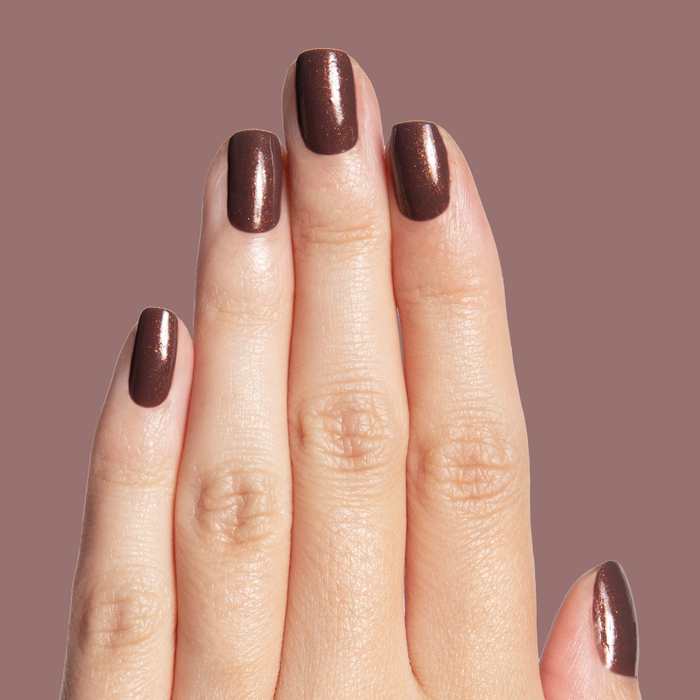 Hand with glossy chocolatey shimmer manicure featuring Goal Getter long-lasting polish on mauve background