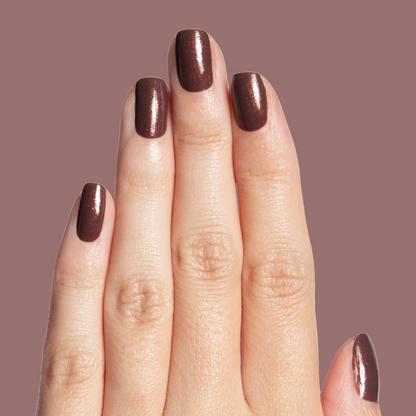 Hand with glossy chocolatey shimmer manicure featuring Goal Getter long-lasting polish on mauve background