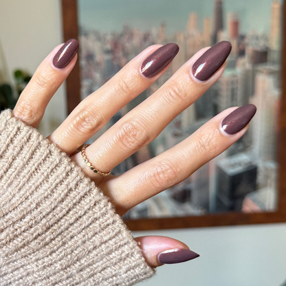 Hand with glossy Goal Getter gel polish manicure in a subtle shimmer brown shade against a soft neutral background