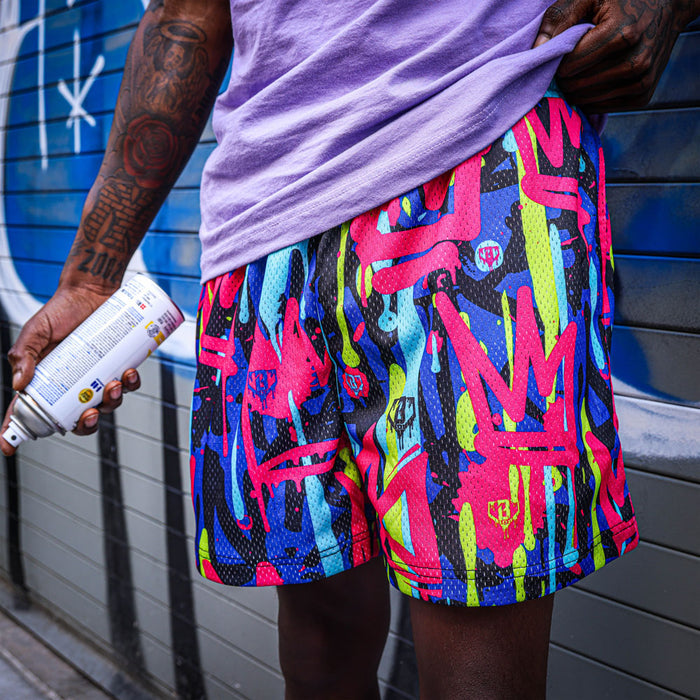 Youth model wearing multi-color youth shorts with “Graffiti Crown” design