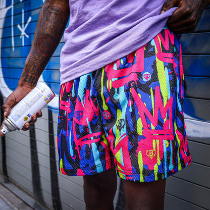 Youth model wearing multi-color youth shorts with “Graffiti Crown” design