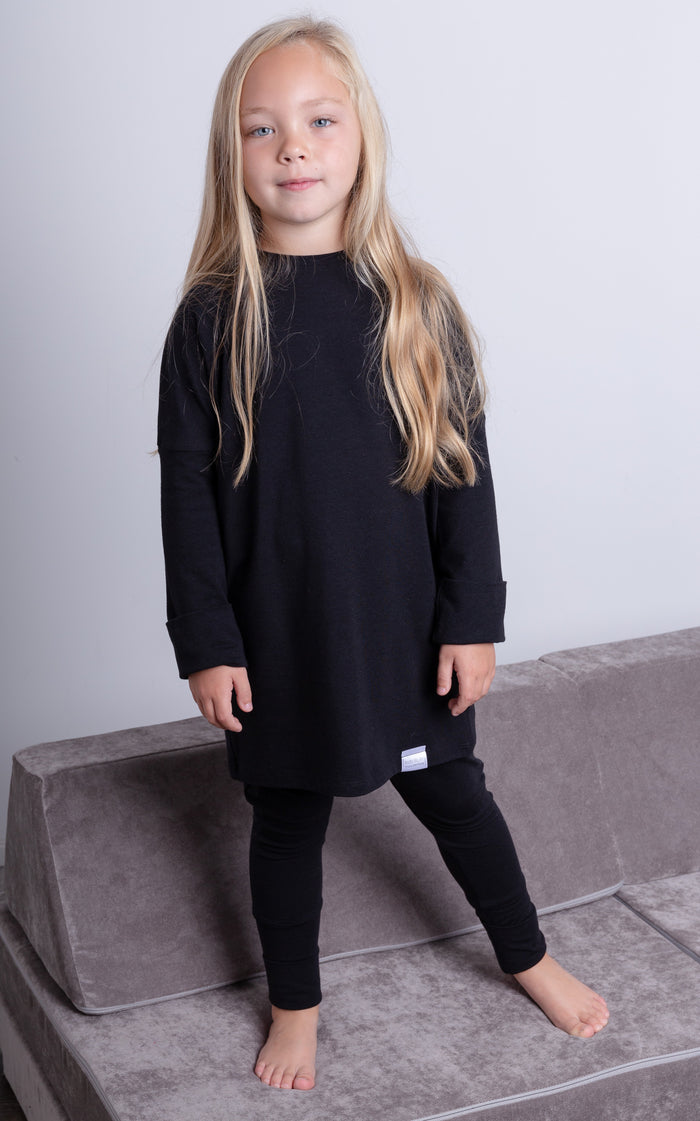 Black grow-with-me shirt for toddlers and kids, designed to be worn as a dress, tunic, or long shirt. Seamless shoulders and soft, eco-friendly fabric. Ethically made in Canada.