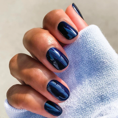 Hand with nails painted in glossy shimmering inky navy using HJ showing a smooth, long-lasting at-home manicure