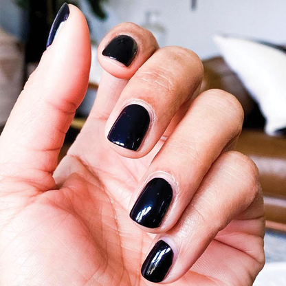 Hand with nails painted in glossy deep navy using HJ for a polished, long-lasting at-home manicure by Olive and June