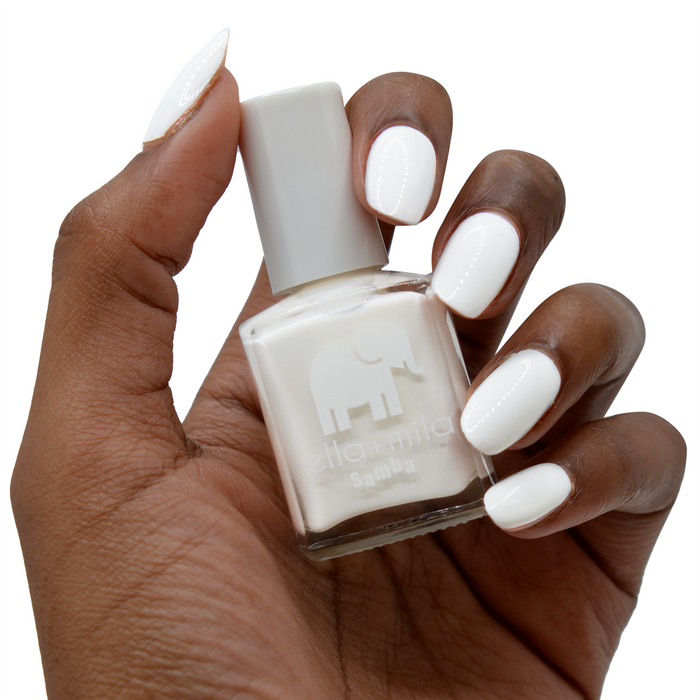 I Need a Tan white nail polish on a deep skin tone, hand holding the bottle