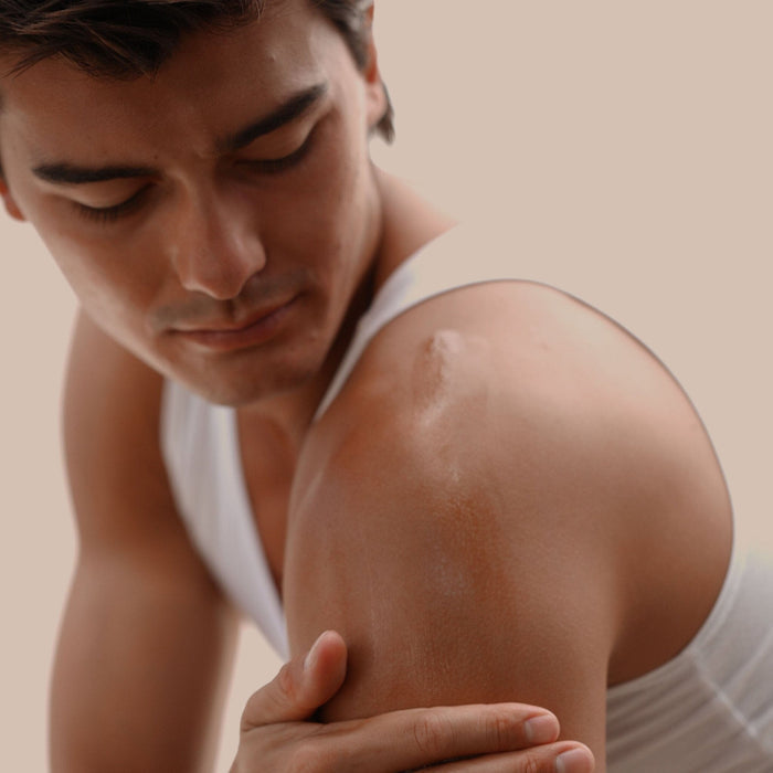 Man rubbing 'Iliahi Sandalwood Dry Oil on shoulder