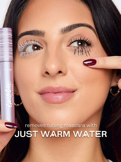 Woman applying mascara with a product labeled 'removes tubing mascara with just warm water'.