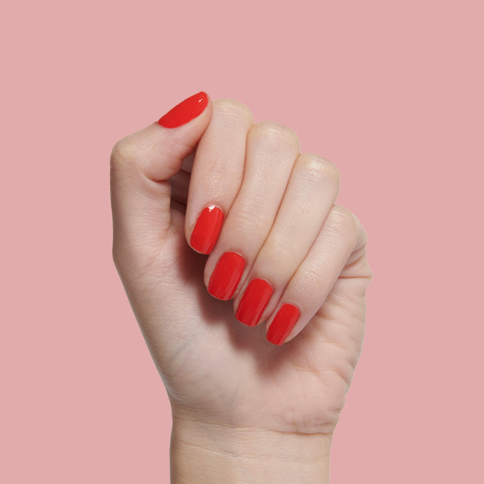 Hand with nails painted in bright cranberry Kiss Cam polish for a vibrant, long-lasting manicure look