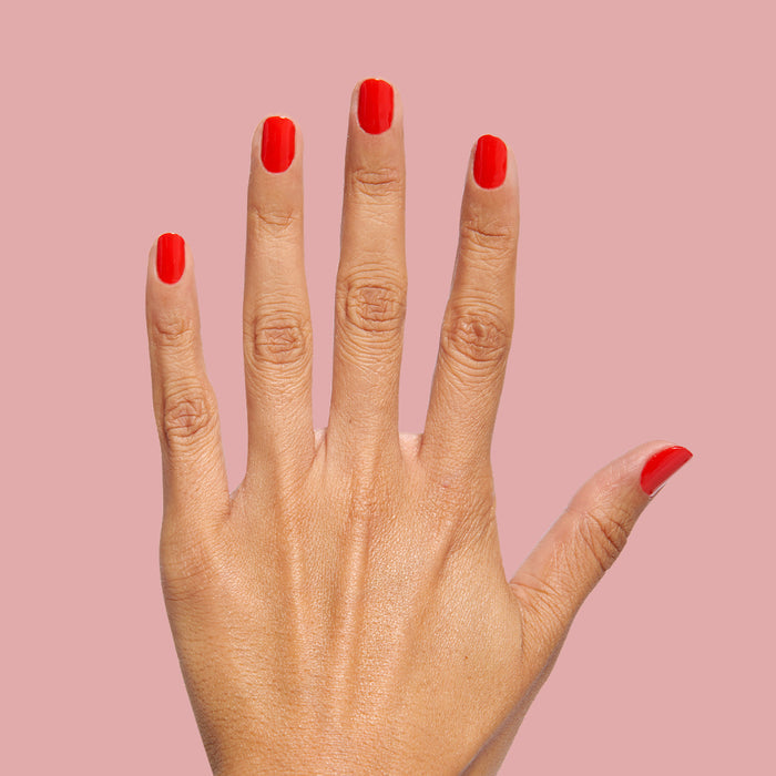 Hand with nails painted in bright red Kiss Cam polish for a long-lasting, vibrant at-home manicure look