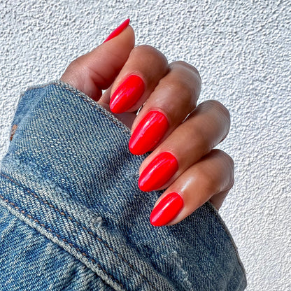 Hand with almond-shaped nails painted in bright red Kiss Cam polish for a shiny, long-lasting at-home manicure look