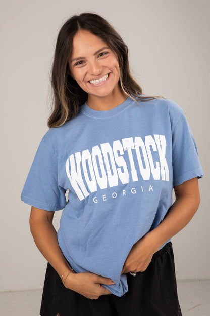 Woman wearing a blue t-shirt with 'Woodstock Georgia' text against a plain background
