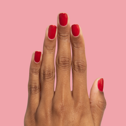 Hand with nails painted in glossy red shimmer Lippy polish for a bold at-home manicure by Olive and June