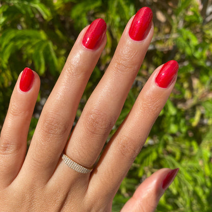 Hand with nails painted in glossy red shimmer Lippy polish showcasing a fresh at-home manicure in natural light