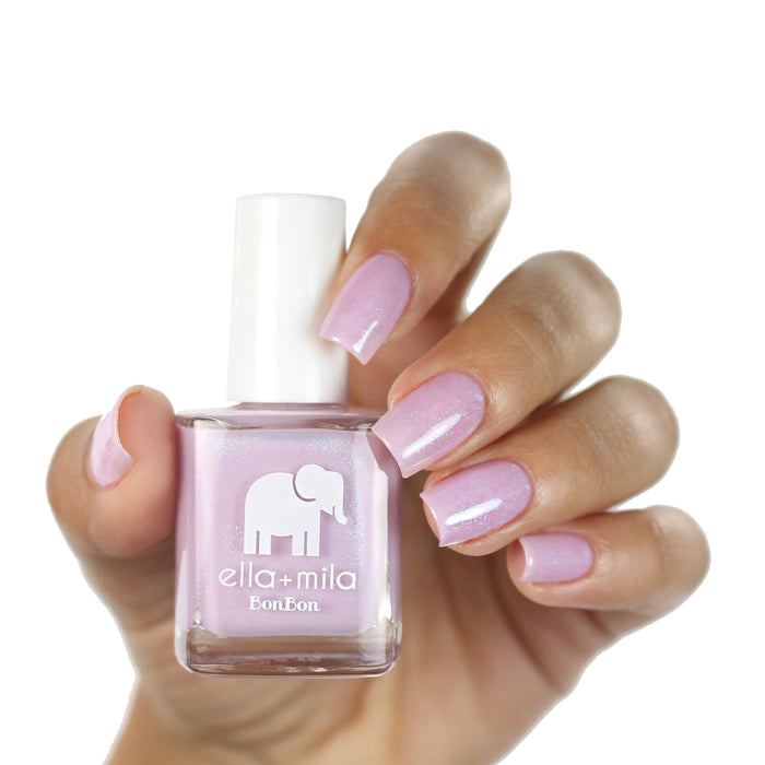 Midnight in Paris lavender pink nail polish on a medium-deep skin tone, hand holding the bottle
