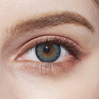 Close-up of a light-skinned eye with bushy eyebrow, subtle eyelid makeup, and striking NEO Vision Cosmo Blue coloured contact lenses by NEO Vision.