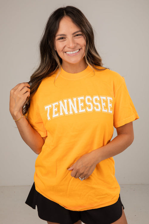 Woman wearing a yellow 'TENNESSEE' t-shirt against a plain background