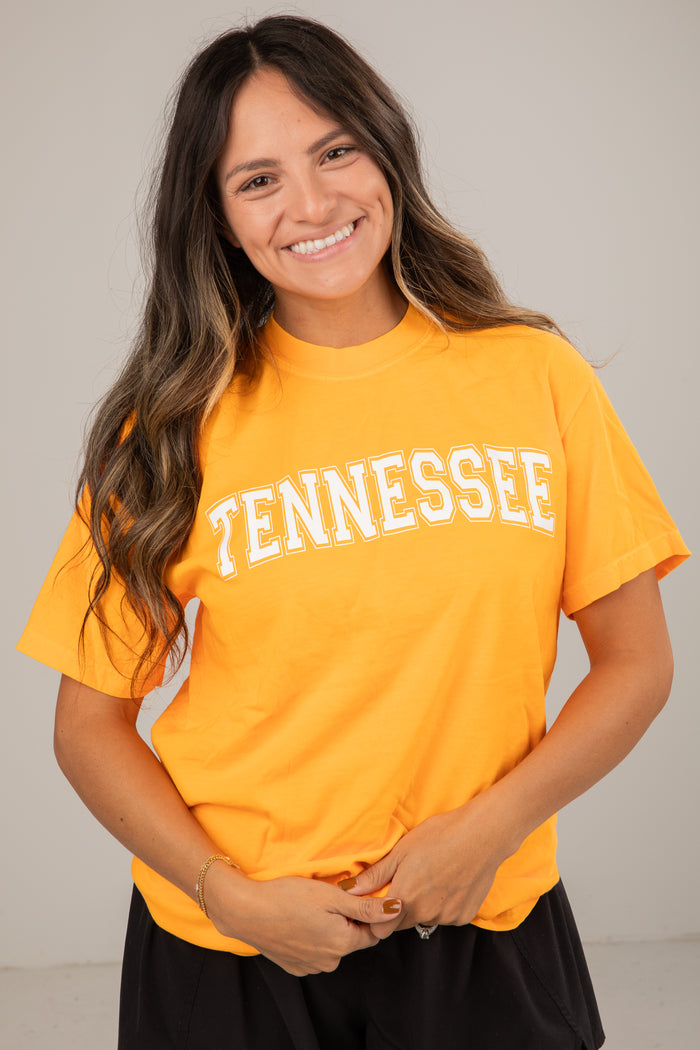 Woman wearing a yellow 'TENNESSEE' t-shirt against a plain background