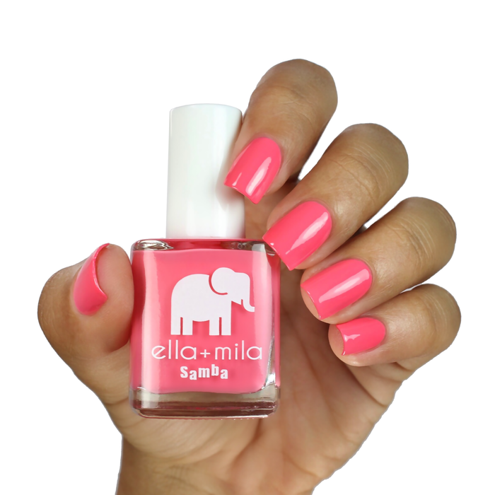 Pinktini coral pink nail polish on a medium skin tone, hand holding the bottle