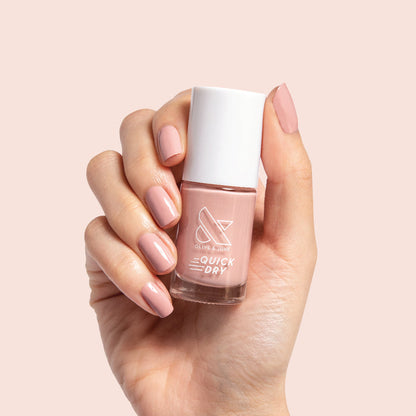 Hand holding Poodle polish bottle with nails painted in neutral beigey pink for an easy, polished at-home mani look