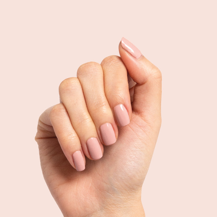 Hand with nails polished in Poodle neutral beigey pink for a chic and effortless at-home manicure look