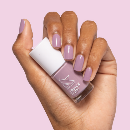 Hand holding Prairie nail polish with nails painted in soft blooming purple for a quick dry mani by Olive and June