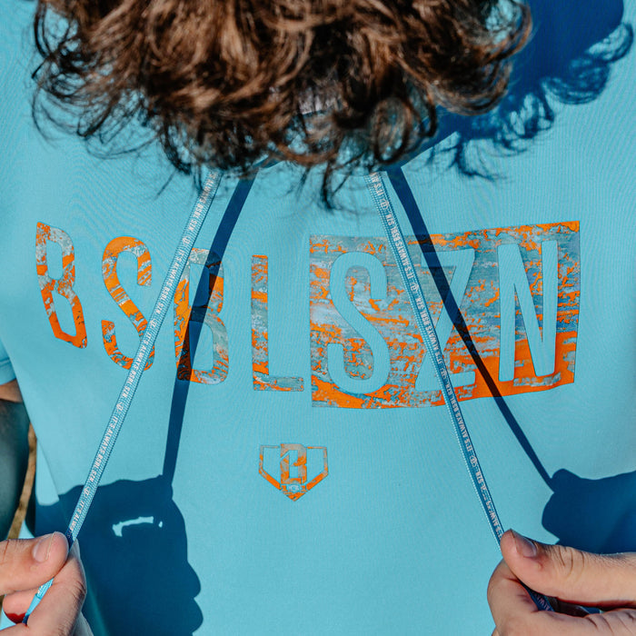 Person wearing a blue hoodie with orange 'BSBLSZN' text and graphics