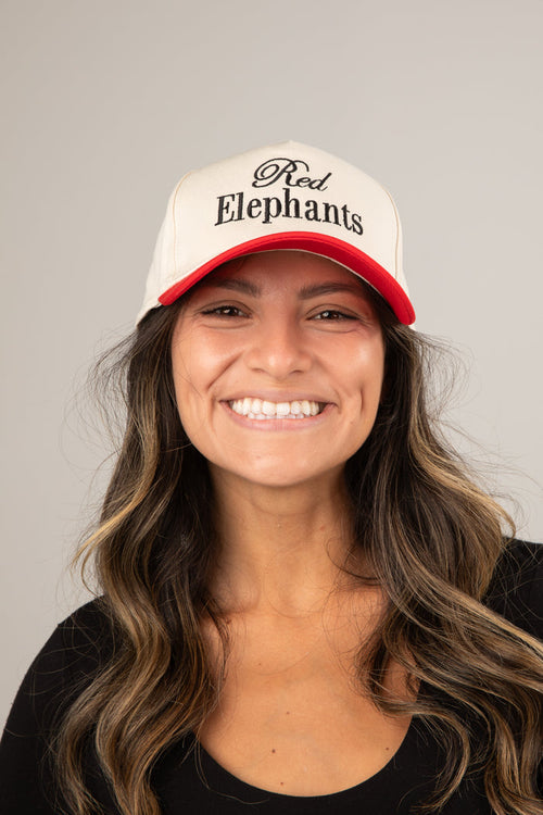 Woman wearing a cap with 'Red Elephants' text against a gray background