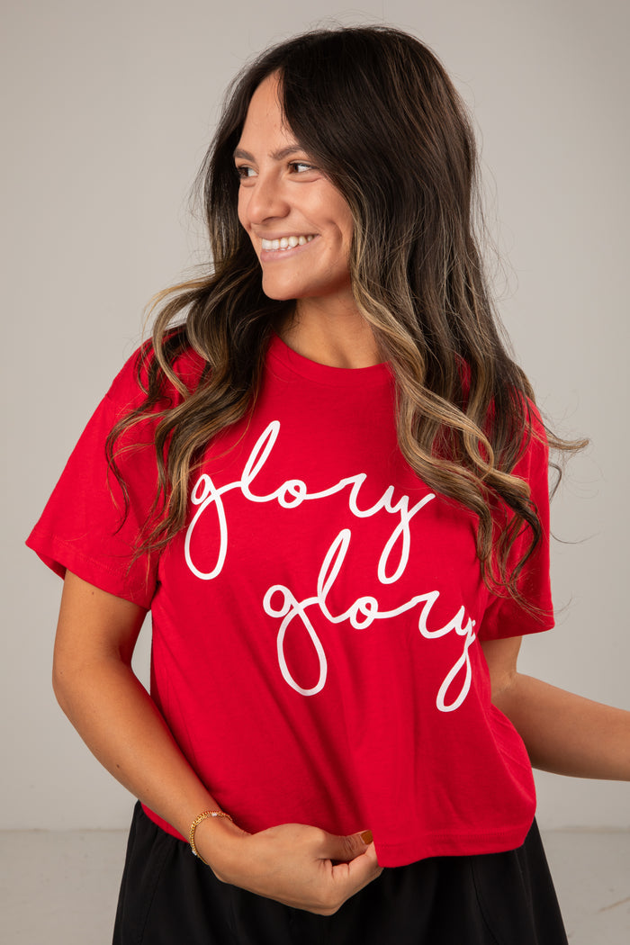 Woman wearing a red t-shirt with 'glory glory' text on a plain background