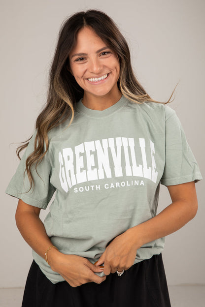 Woman wearing a green t-shirt with 'Greenville, South Carolina' text against a plain background