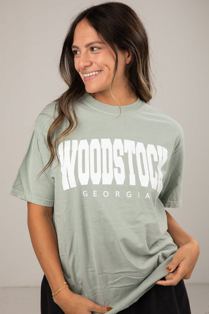 Woman wearing a green t-shirt with 'Woodstock, Georgia' printed on it against a plain background