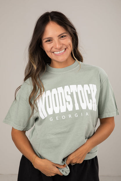 Woman wearing a green t-shirt with 'Woodstock Georgia' text against a plain background