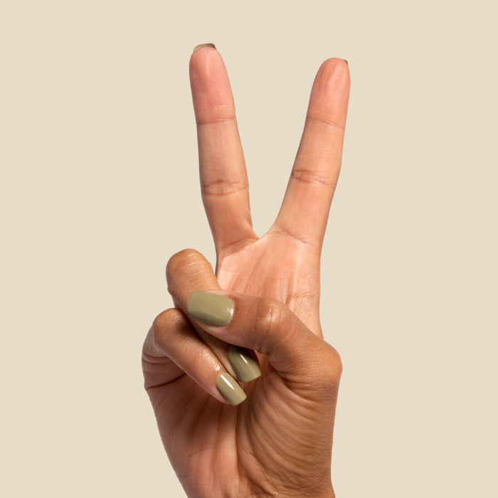 Hand showing two fingers with nails painted in mid-tone Sagey green polish for manicure display