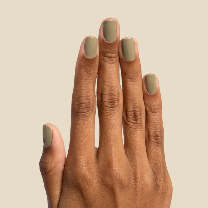 Hand with nails painted in smooth Sagey polish by Olive and June against neutral background for manicure display