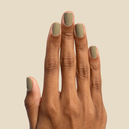 Hand with nails painted in smooth Sagey polish by Olive and June against neutral background for manicure display
