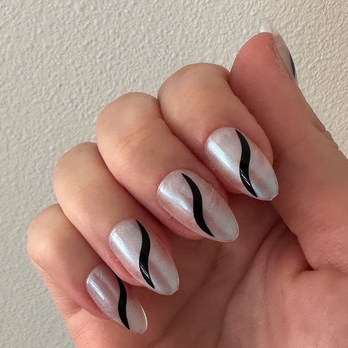 Simple Twist - Press-On | Medium | Almond neutral nails with pearly finish and minimalist black twist design on natural hand