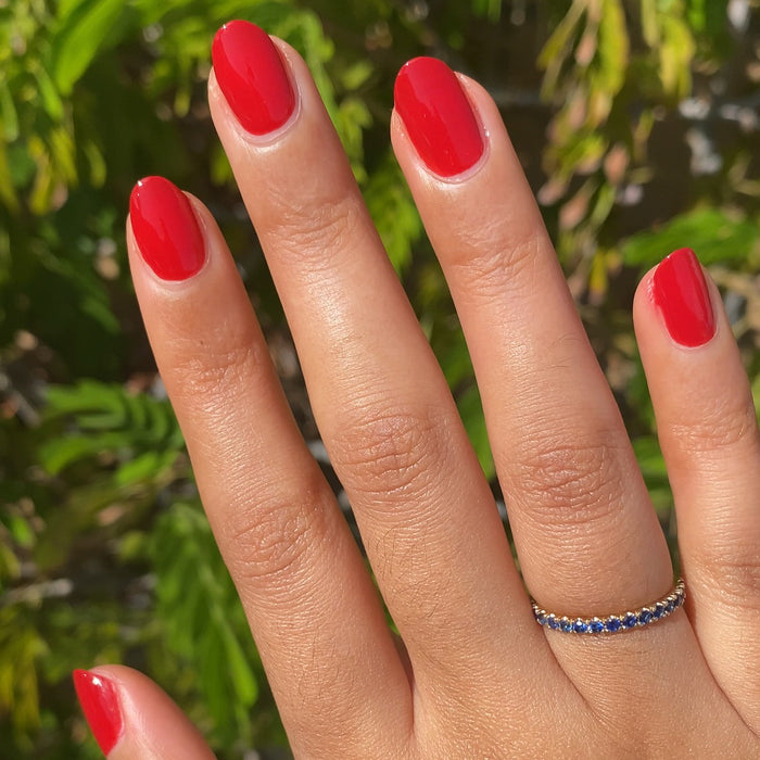Hand with nails painted in vibrant scarlet red Smooch polish showcasing a natural light at-home mani