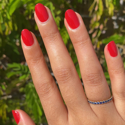 Hand with nails painted in vibrant scarlet red Smooch polish showcasing a natural light at-home mani