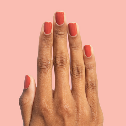 Hand with medium-length nails painted in Southwest warm terracotta polish for a smooth at-home manicure look