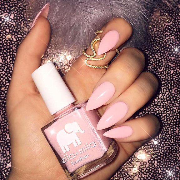 Sugar Puff baby pink almond manicure with a gold ring on a glitter background