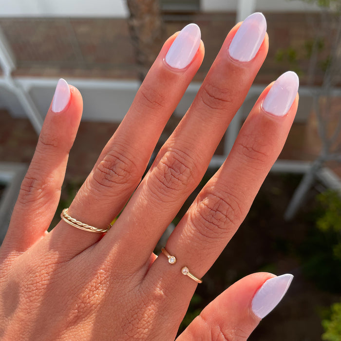 Hand with nails painted in soft white Swan polish showcasing a polished quick dry manicure in natural light