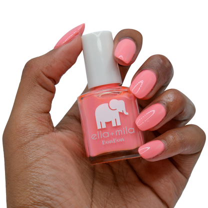 Sweet Tooth peach pink nail polish on a deep skin tone, hand holding the bottle